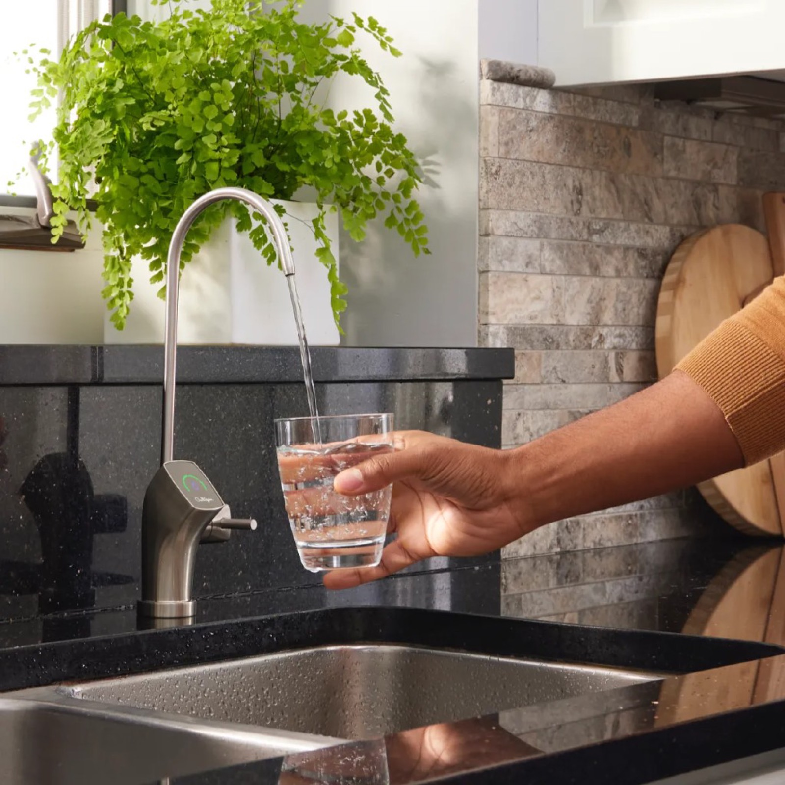Pouring filtered drinking water from a kitchen faucet into a glass